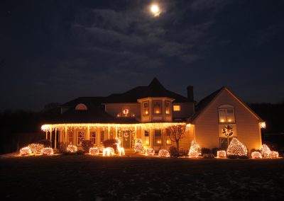 Christmas House lit up with white lights, moon in the sky